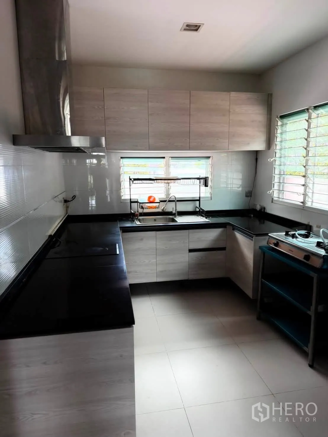 Detached House for rent in Bang Phli, Samut Prakan - Main kitchen with U-shaped counters, cabinets and sink by windows.