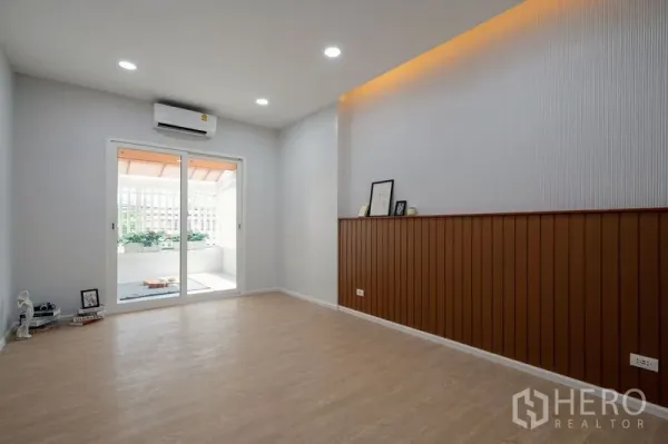 Townhouse for sale in Din Daeng, Bangkok - Spacious multipurpose room with air-conditioning, wood flooring and access to the balcony in a Bangkok townhouse.