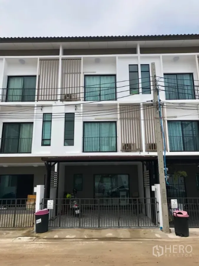 Townhouse for sale in Bang Kapi, Bangkok - Modern three-story townhouse facade with gated carport and large windows in a quiet Bang Kapi community.
