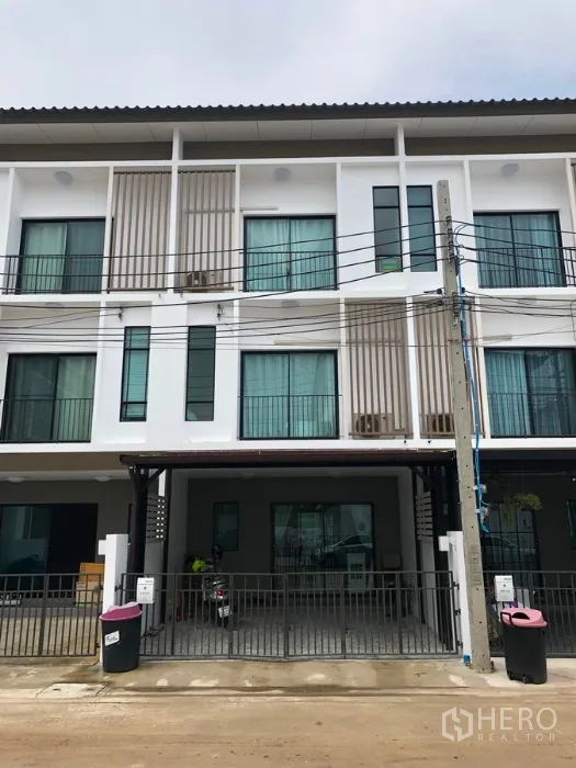 Townhouse for sale in Bang Kapi, Bangkok - Modern three-story townhouse facade with gated carport and large windows in a quiet Bang Kapi community.