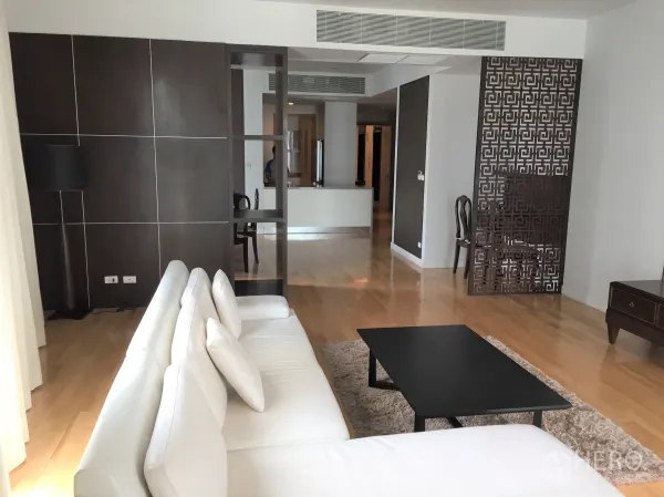 คอนโด ให้เช่าหรือขายในKhlong Toei, Bangkok - ห้องนั่งเล่นกว้าง โซฟาสีขาว โต๊ะกลางสีดำ พื้นไม้ และฉากกั้นลายสวยในคอนโดสมัยใหม่