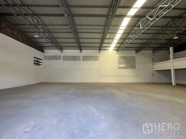 货栈 出租在Mueang Pathum Thani, Pathum Thani - 开阔仓库地面，挑高屋顶，通风砖窗与长条照明。