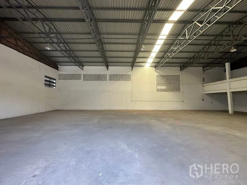 货栈 出租在Mueang Pathum Thani, Pathum Thani - 开阔仓库地面，挑高屋顶，通风砖窗与长条照明。