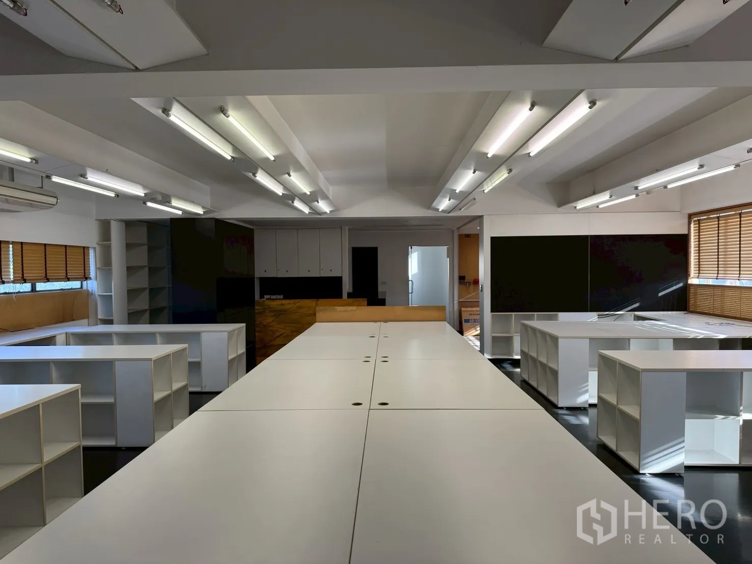 Office Space for rent in Huai Khwang, Bangkok - Central conference-length worktable surrounded by cubby storage in a bright office.