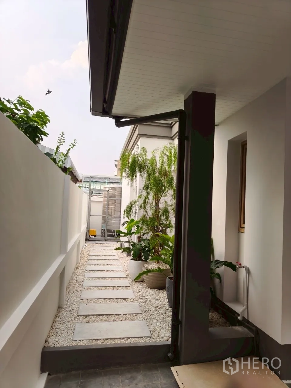 独立式住宅 出售在Suan Luang, Bangkok - 侧院卵石步道与盆栽绿植。