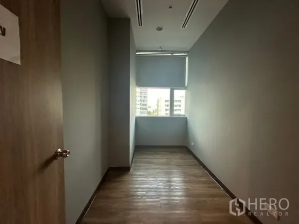 Office Space for rent in Ratchathewi, Bangkok - Narrow manager’s room with wood flooring and city view window.