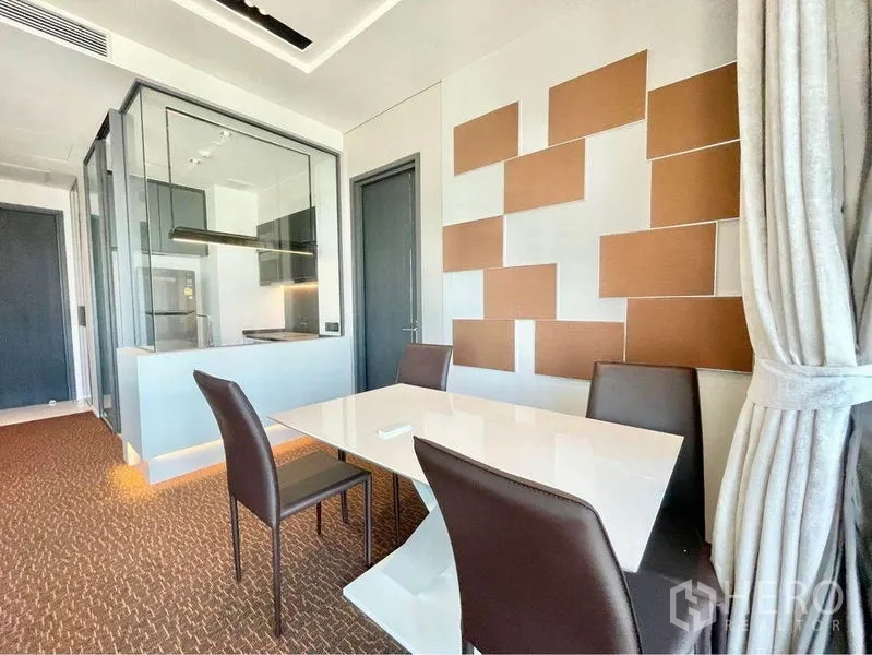 Condominium for rent in Watthana, Bangkok - Dining corner with sleek white table and leather chairs beside glass-partitioned kitchen.