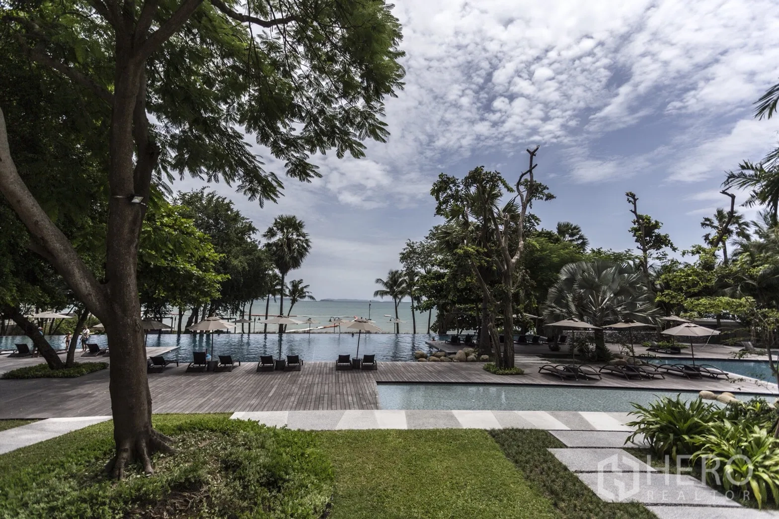 Condominium for rent in Bang Lamung, Chon Buri - Beachfront resort-style pool with sun loungers, greenery, and sea view in Naklua.