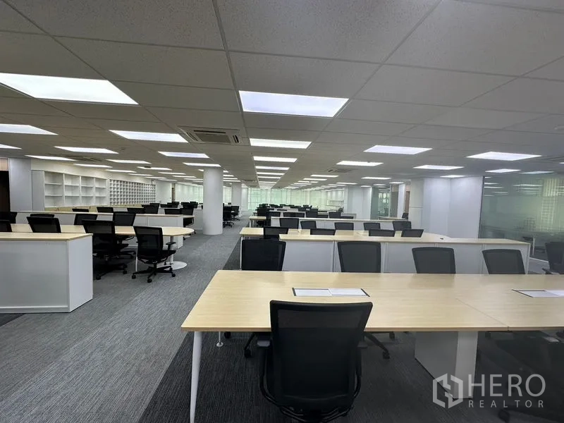 Office Space for rent - Deep floor plate with multiple desks and shelving in a bright office interior.