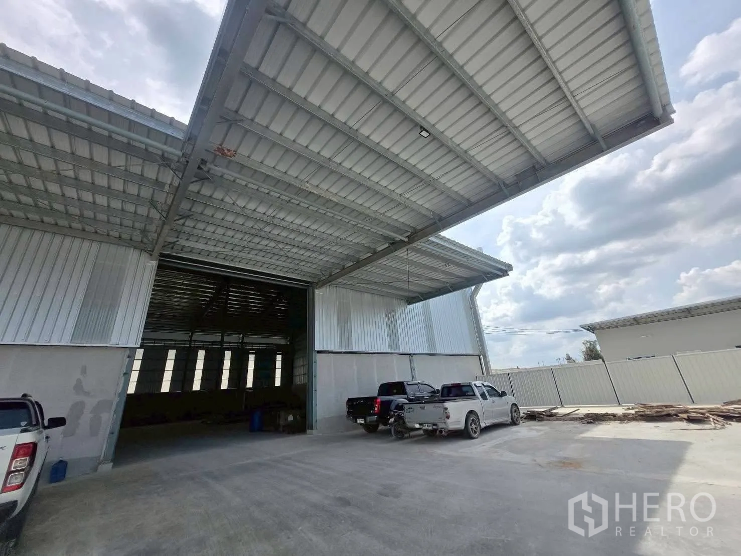 Warehouse for rent in Bang Bo, Samut Prakan - Covered loading area with wide canopy and pickup trucks parked at entrance.