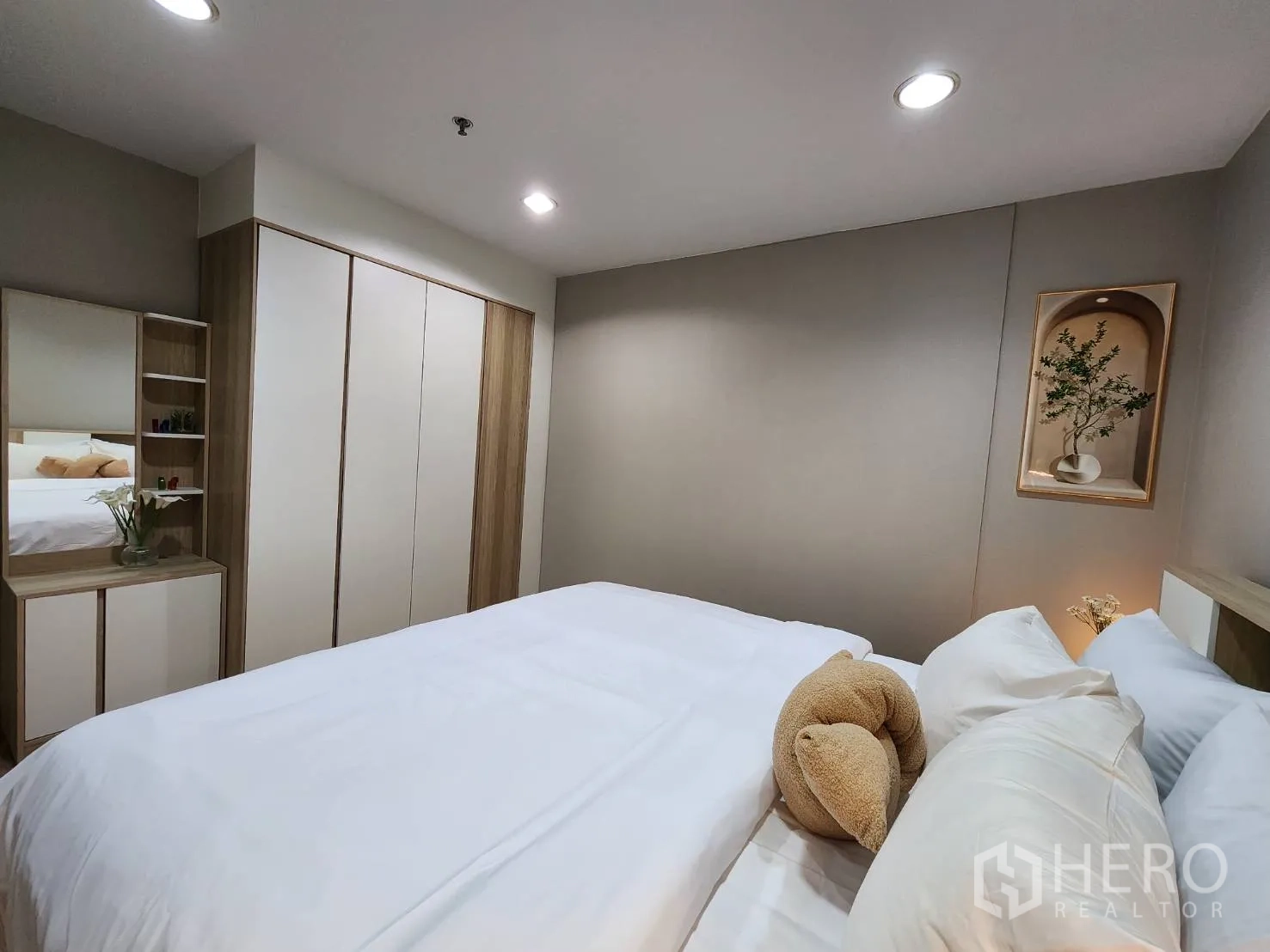 Condominium for rent in Watthana, Bangkok - Second bedroom with white bedding, large wardrobe and dressing table with mirror.