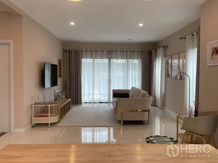Detached House for rent in Bang Phli, Samut Prakan - Living room with TV wall, media console and sliding glass doors.