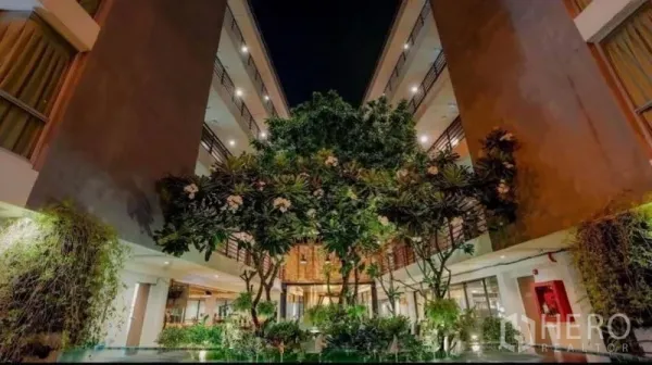 零售空间 出售在Phra Nakhon, Bangkok - 夜色开放式庭院，鸡蛋花树与环绕的多层建筑。