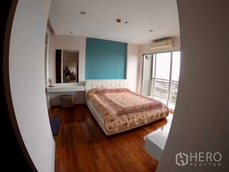 Condominium for rent or sale in Khlong San, Bangkok - Spacious bedroom with blue feature wall and access to a city-view balcony.