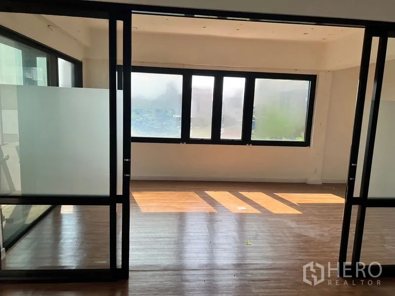 Office Space for rent in Sathon, Bangkok - Sunlit workspace with large windows, frosted glass sliding partitions, and wood floors.