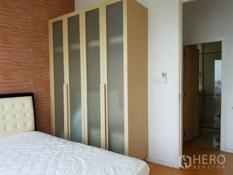 Condominium for rent in Chatuchak, Bangkok - Second bedroom showing tall frosted‑glass wardrobes and access to the bathroom.