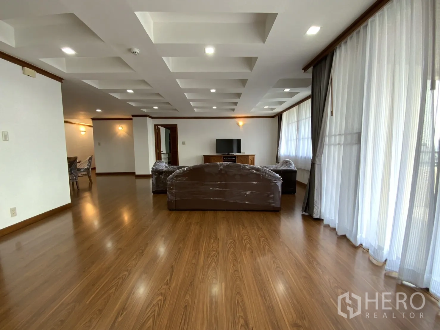 คอนโด ให้เช่าในWatthana, Bangkok - ห้องนั่งเล่นแบบโอเพ่นสเปซ พื้นไม้ ฝ้าเพดานหลุม และม่านโปร่งเต็มความสูง ในคอนโดเขตวัฒนา กรุงเทพฯ