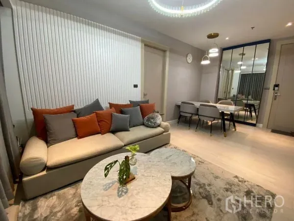 公寓 出售在Huai Khwang, Bangkok - 开放式客餐厅，沙发与水晶吊灯相映，配大理石桌与镜面墙，空间感十足。