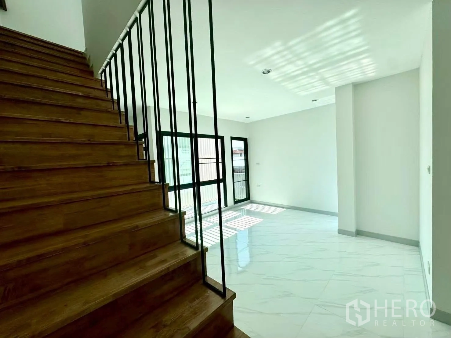 Home Office for rent in Wang Thonglang, Bangkok - Wooden staircase with metal balustrade beside a light-filled living area.