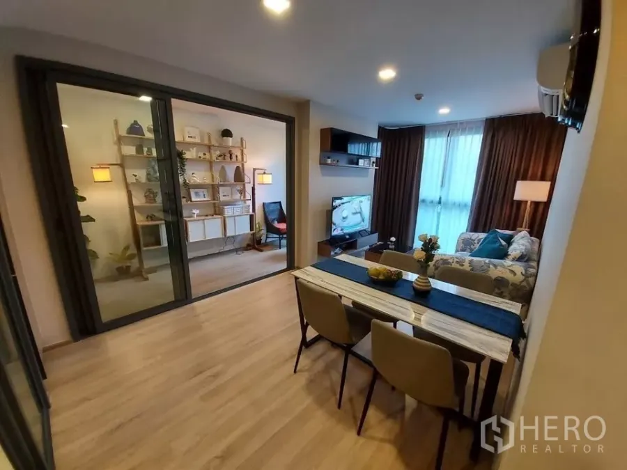 Condominium for rent in Watthana, Bangkok - Open-plan living and dining with glass-partitioned study, wood floors, sofa and TV.