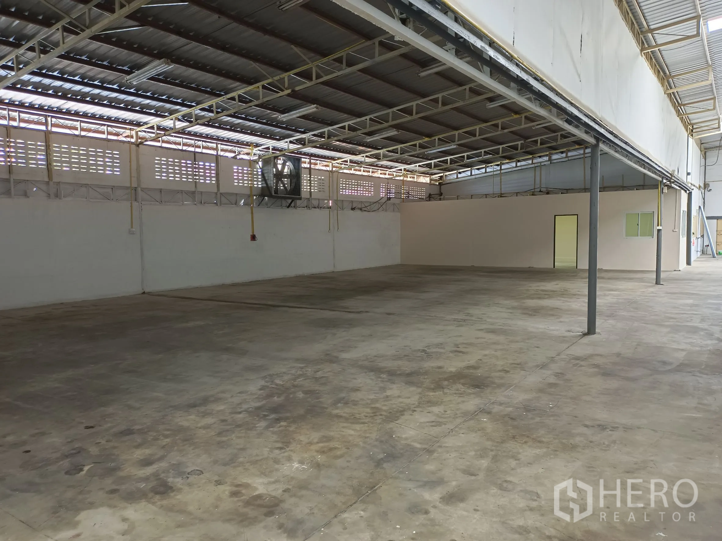Warehouse for rent in Suan Luang, Bangkok - Open warehouse interior with steel trusses, polished concrete floor and a side office.