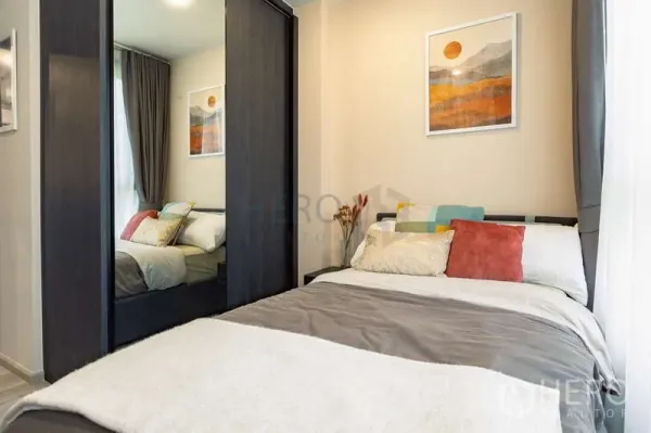Condominium for rent or sale - Cozy bedroom with mirrored wardrobe, soft bedding and window curtains in the 2-bedroom XT Huaikhwang unit.