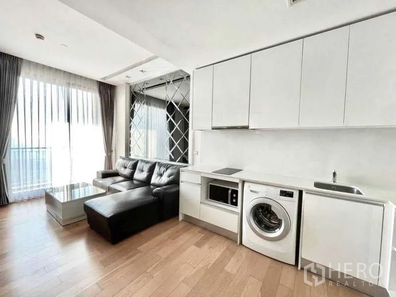 Condominium for rent in Bangkok - Living space with floor-to-ceiling curtains, white cabinetry and corner sofa.