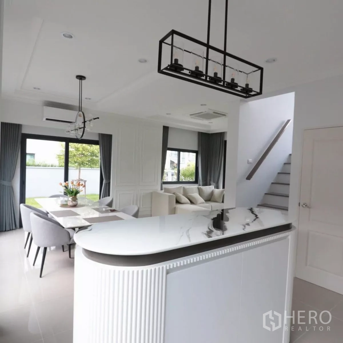 Detached House for rent in Bang Phli, Samut Prakan - Kitchen island facing dining space with pendant lights and nearby staircase