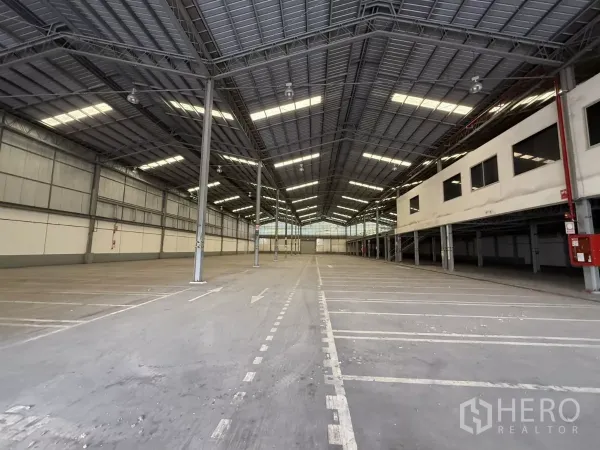 工厂 出租在Lat Krabang, Bangkok - 高挑仓库内部，钢结构屋顶、LED高棚灯，地面划线装卸道，一侧为架高办公区