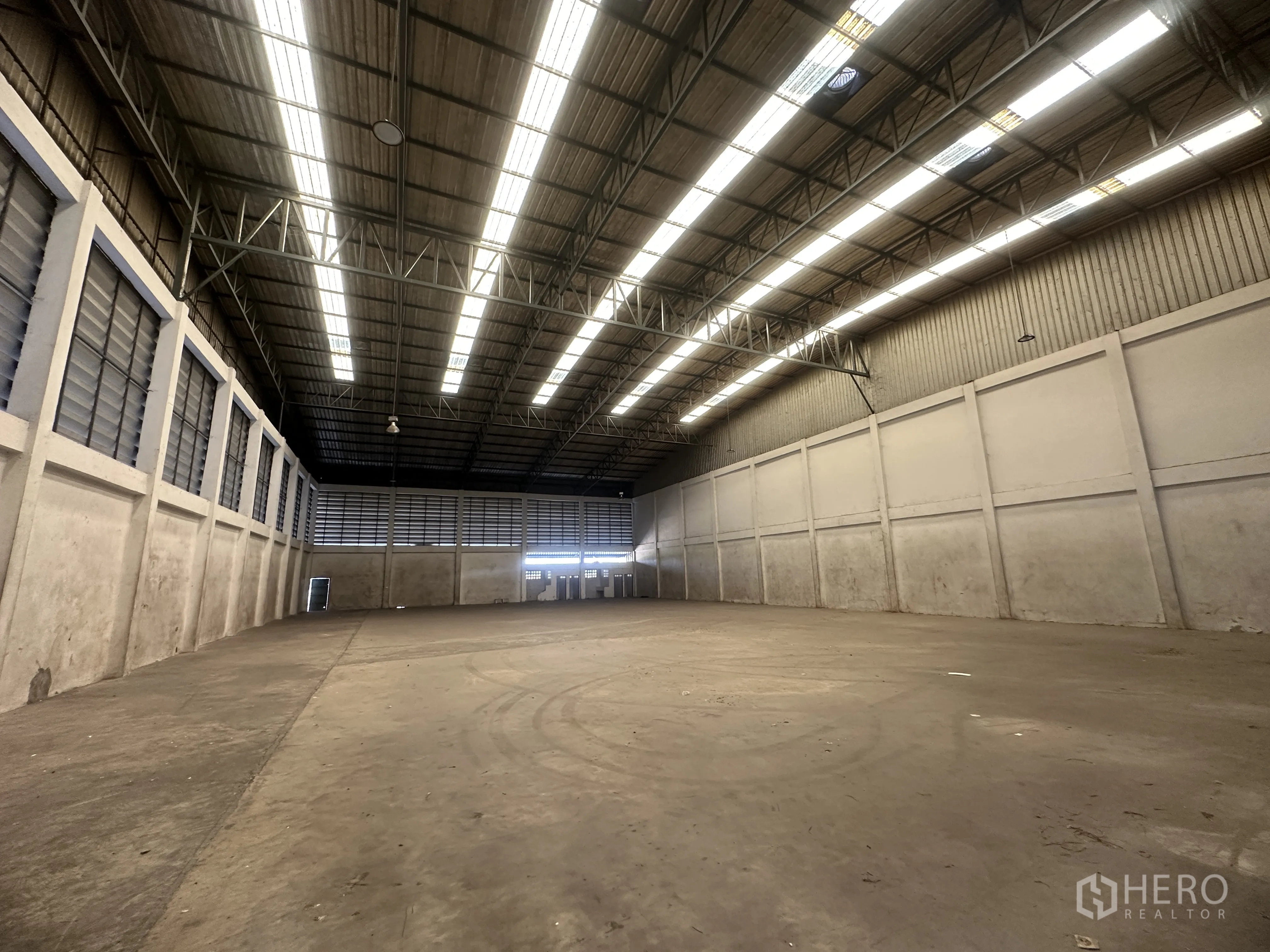 Factory for rent in Wang Noi, Phra Nakhon Si Ayutthaya - Open production hall with bright strip lighting, ventilated walls, and a concrete floor.