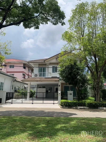 Detached House for rent in Bang Kapi, Bangkok - Two-storey detached house in Bang Kapi with a gated driveway and mature trees lining the street.