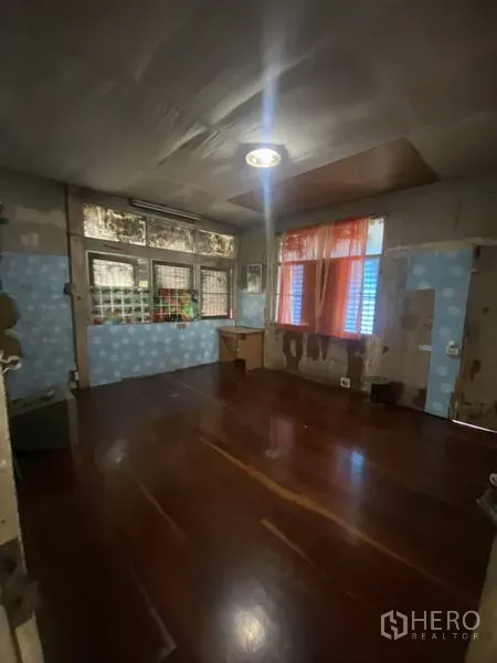 บ้าน ให้เช่าในKhlong Toei, Bangkok - ห้องอีกมุมหนึ่งพื้นไม้ หน้าต่างมีเหล็กดัด และผนังเก่าต้องปรับปรุง