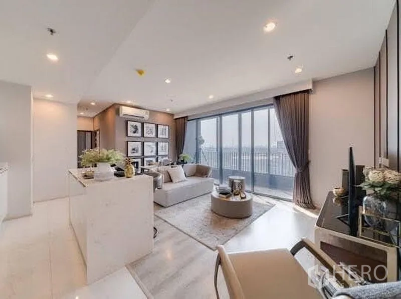 公寓 出租在Bang Na, Bangkok - 开放式客厅与大理石中岛厨房，沙发区通向阳台的推拉落地门。