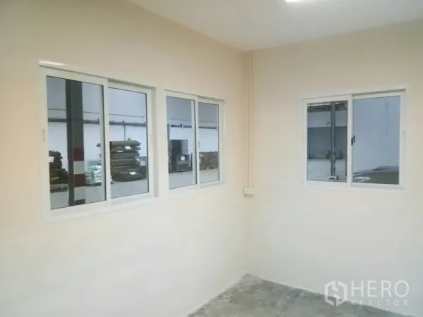 Warehouse for rent in Suan Luang, Bangkok - Office room windows overlooking the warehouse floor with power outlets on the wall.