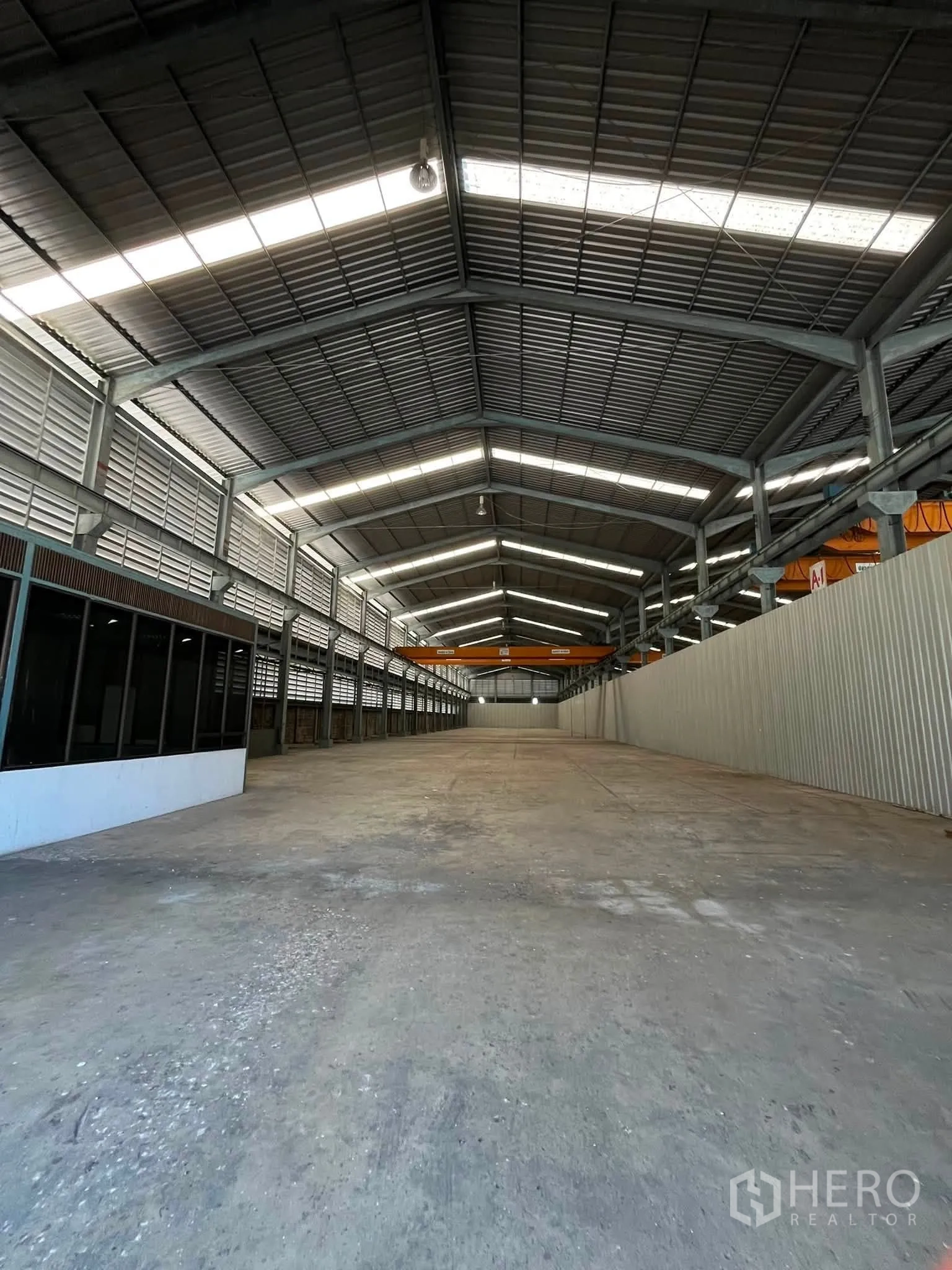 Warehouse for rent in Bang Phli, Samut Prakan - Central aisle of the warehouse with office frontage and cranes at the far end.
