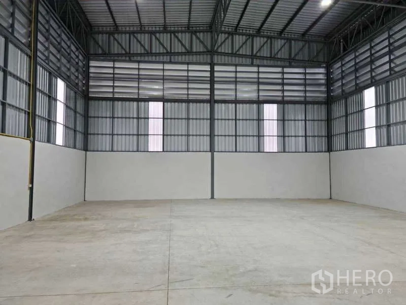 货栈 出租在Bang Bua Thong, Nonthaburi - 园区外观，宽阔停车与作业区，货车与面包车停靠在新建金属仓库前。