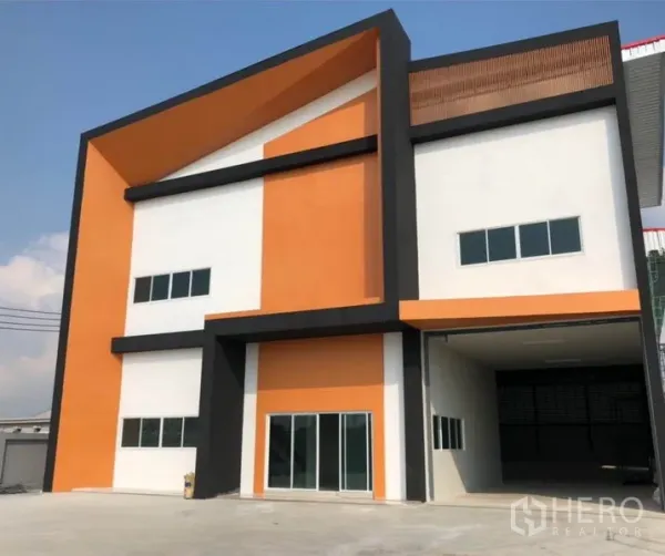Factory for rent or sale in Krathum Baen, Samut Sakhon - Close-up of contemporary factory exterior showing glass sliding doors, high covered loading bay and multiple windows.