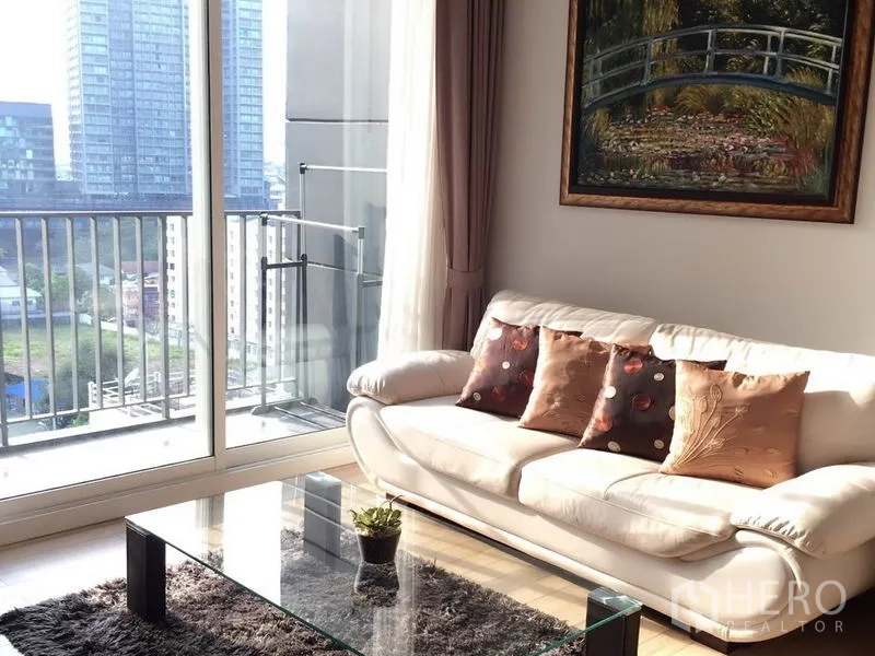 คอนโด ให้เช่าในKhlong Toei, Bangkok - โซฟาข้างประตูกระจกเต็มสูง เปิดออกสู่ระเบียงชมวิวสกายไลน์.