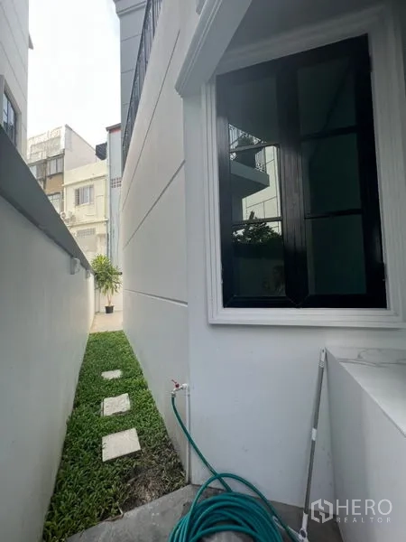 สำนักงานที่บ้าน ให้เช่าหรือขายในWatthana, Bangkok - ลานหญ้าด้านข้างพร้อมแผ่นทางเดินตลอดผนังภายนอกสีขาว