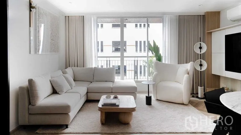 คอนโด ขายในRatchathewi, Bangkok - ห้องนั่งเล่นสว่าง โซฟาเข้ามุม เก้าอี้อาร์มเชียร์ พรม และประตูกระจกออกระเบียง