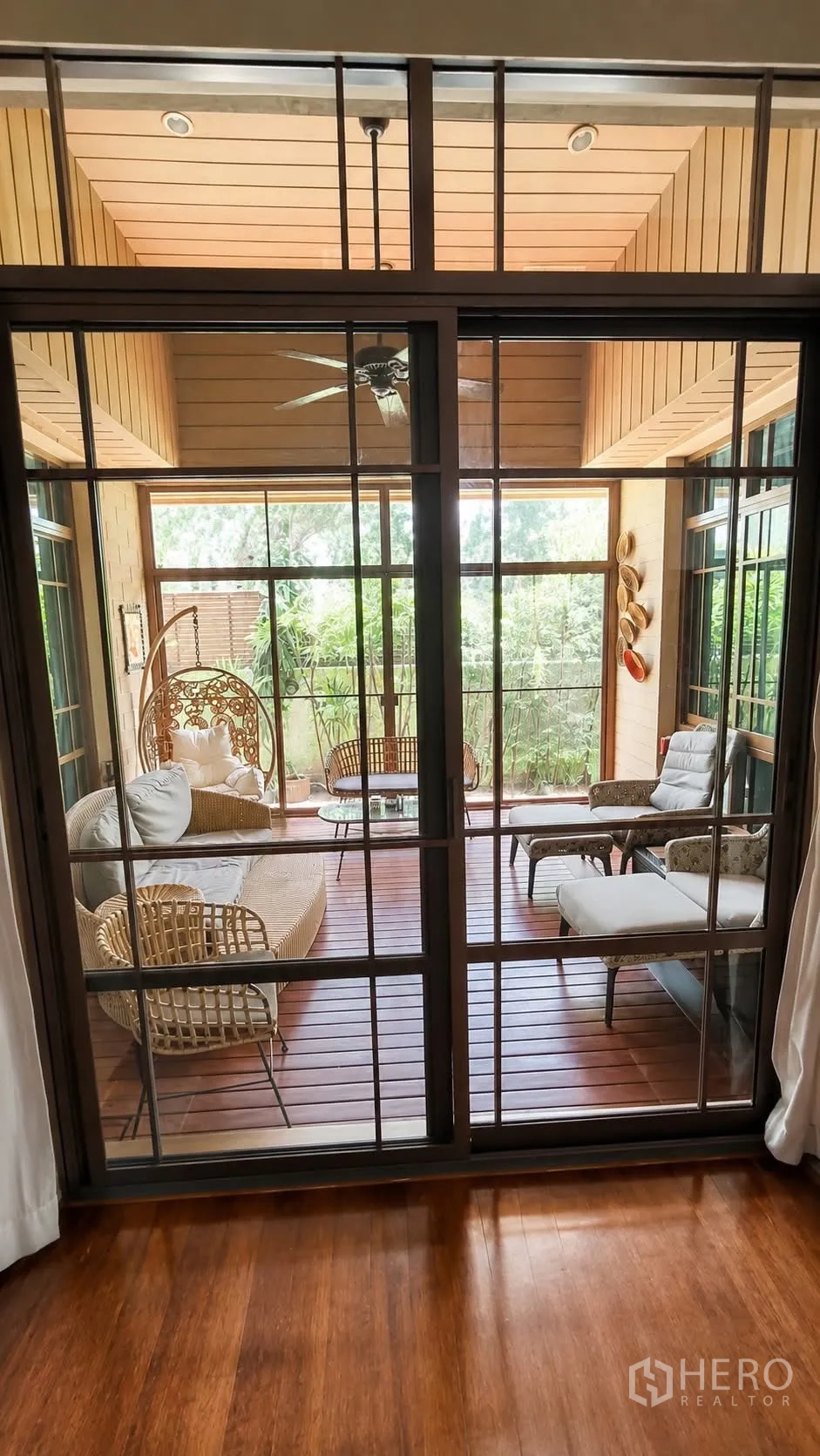 Detached House for rent in Watthana, Bangkok - Enclosed terrace with rattan seating and garden views.
