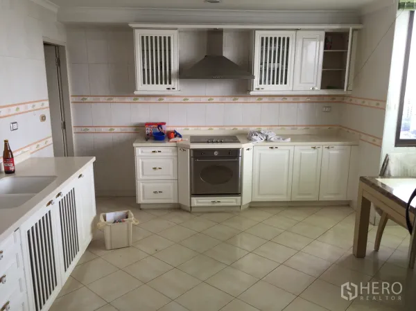 公寓 出租在Khlong Toei, Bangkok - 明亮厨房，白色橱柜、烤箱、抽油烟机与瓷砖地面，靠窗