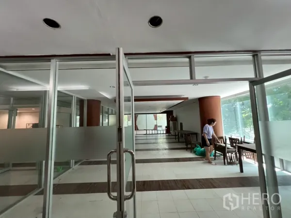 Retail Space for rent - Entrance through glass doors to a spacious showroom with floor-to-ceiling windows and round columns.