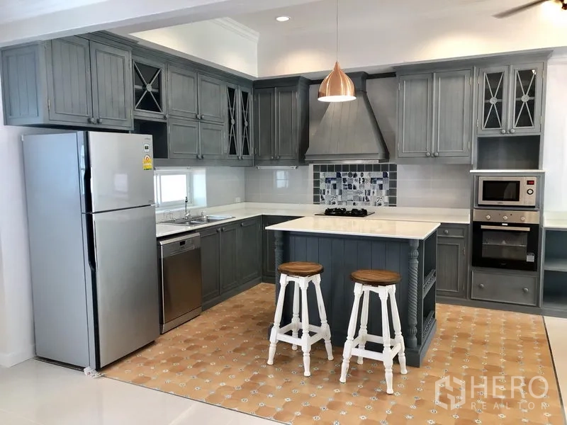 บ้าน ให้เช่าในMueang Samut Prakan, Samut Prakan - ครัวสไตล์ชั้นตู้สีเทา มีไอส์แลนด์ ท็อปหินสีขาว และเครื่องใช้สแตนเลสครบ