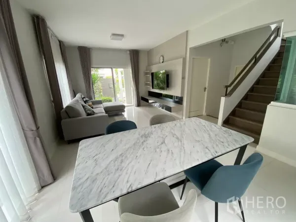 บ้าน ให้เช่าในPrawet, Bangkok - มุมทานอาหารโต๊ะหินอ่อน เก้าอี้สี่ตัว มองไปยังผนังทีวีและบันไดไม้