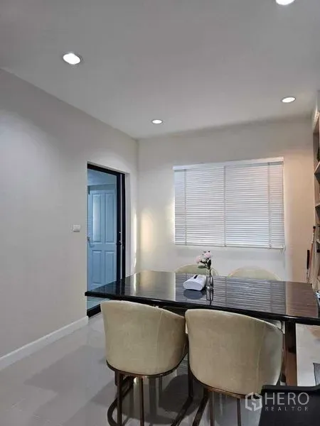 独立式住宅 出售在Khan Na Yao, Bangkok - 餐区一角，大理石餐桌与软包餐椅，百叶窗采光。