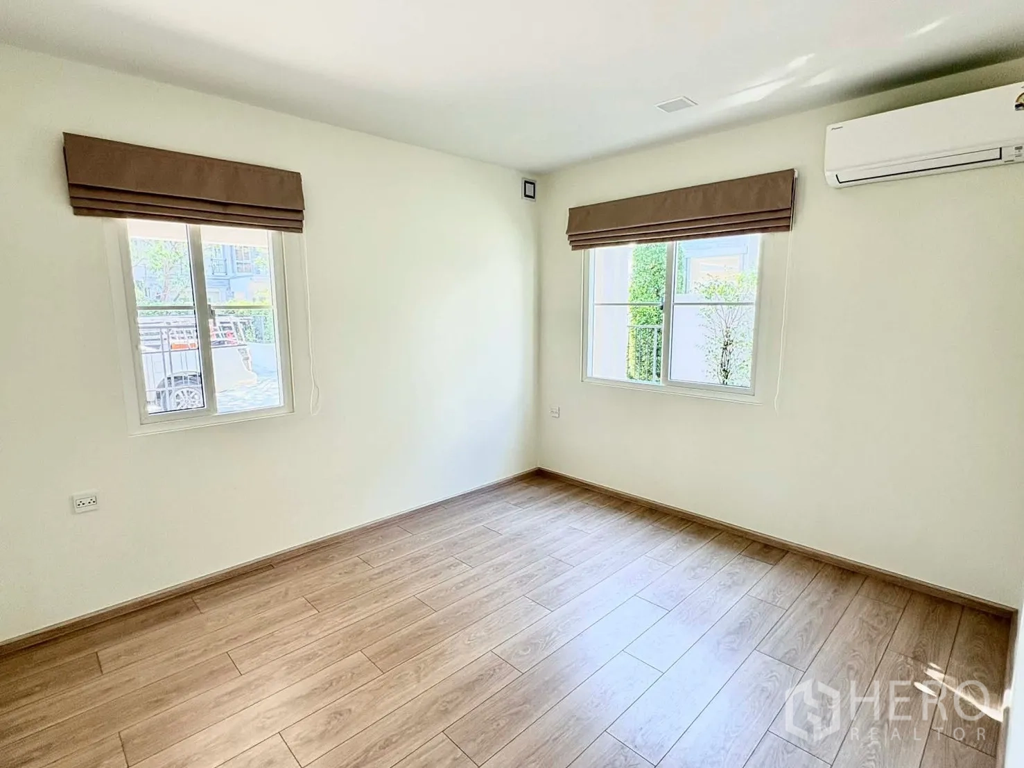 独立式住宅 for rent in Bang Phli, Samut Prakan - 空房间带木纹地板、两扇窗与壁挂空调。