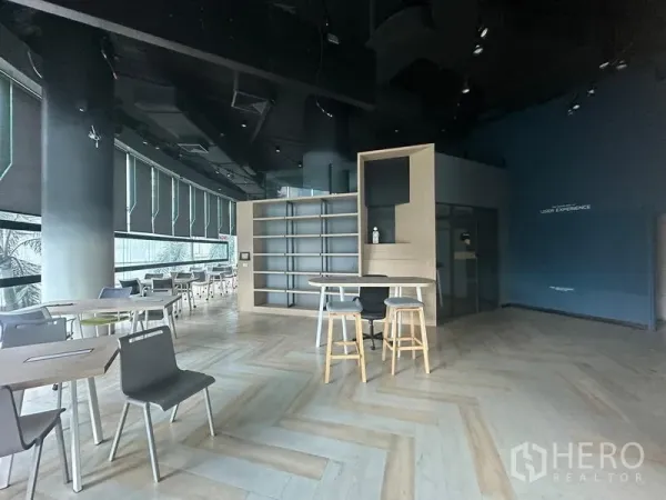 Office Space for rent - Open-plan office with herringbone wood floors, high black ceiling, built-in shelves, island counter and large window shades.