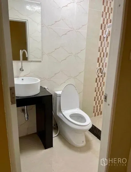 Townhouse for rent - Compact bathroom with vessel sink, toilet and tiled walk-in shower.