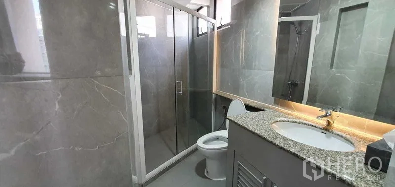 คอนโด ให้เช่าในKhlong Toei, Bangkok - ห้องน้ำพร้อมตู้ฝักบัวกระจก กระเบื้องลายหินอ่อนสีเทา และเคาน์เตอร์อ่างล้างหน้า